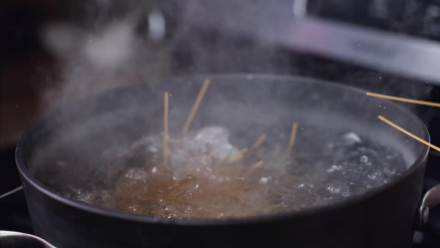 Pasta is dropping into a pot of boiling water