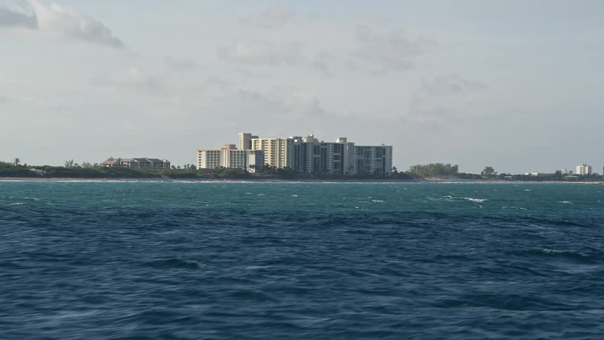 Low flying aerial footage captures beachfront condominiums along the Atlantic Ocean shoreline in Jupiter Florida