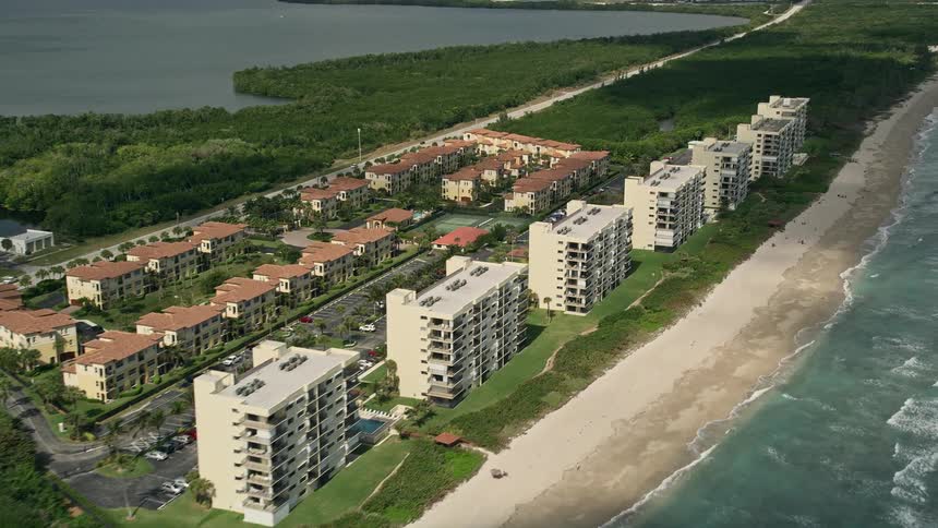 A stunning aerial view of coastal vacation rentals on Jensen Beach Florida with blue waters and partly cloudy skies