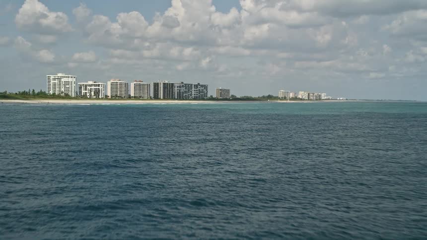 Tilting up from the blue ocean waters revealing beachfront apartment buildings located on the coast of Fort Pierce Florida