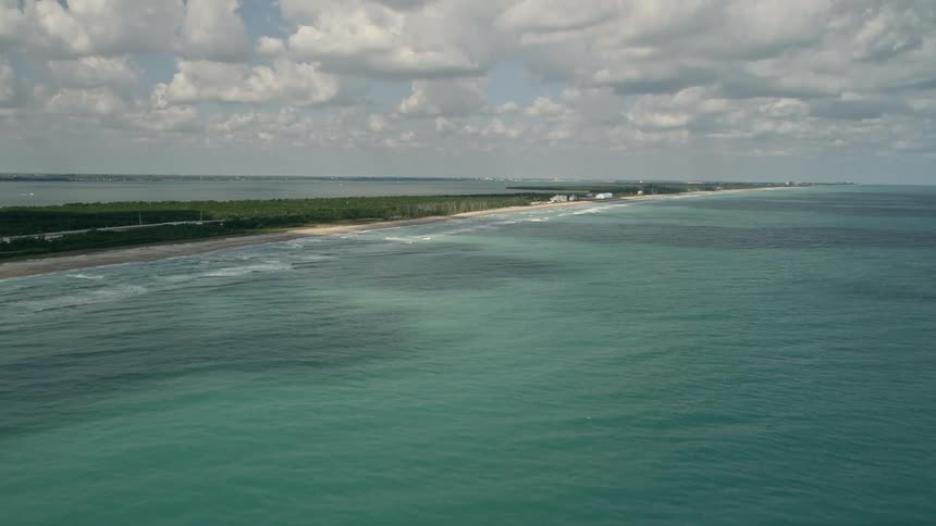An aerial view of beachfront homes in Fort Pierce Florida as the camera tilts up from the blue ocean waters