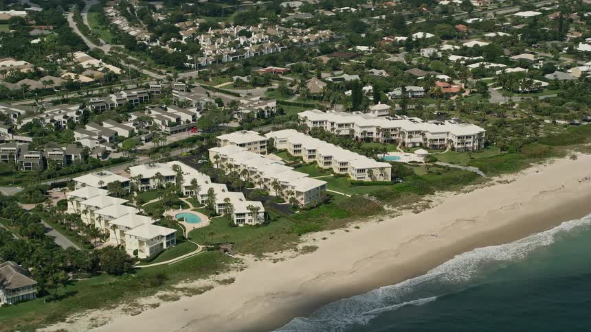 Aerial view of condominium complexes and houses situated along the beach in Vero Beach Florida on a partly cloudy day