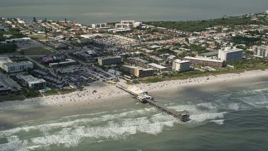 A stunning 5K aerial view of sunbathers enjoying the beach near the Cocoa Beach Pier Florida during summer
