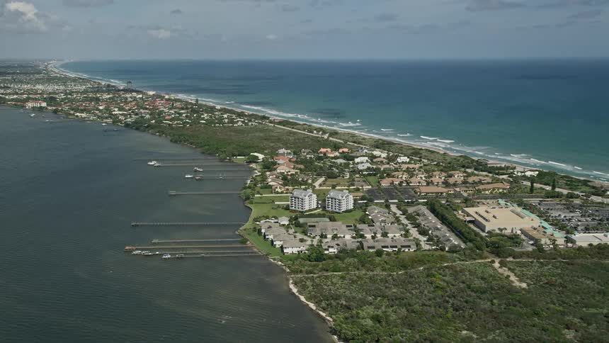Approaching docks and residential neighborhood on the coast of Melbourne Beach Florida captured in stunning 5K aerial footage during a partly cloudy day in the summer