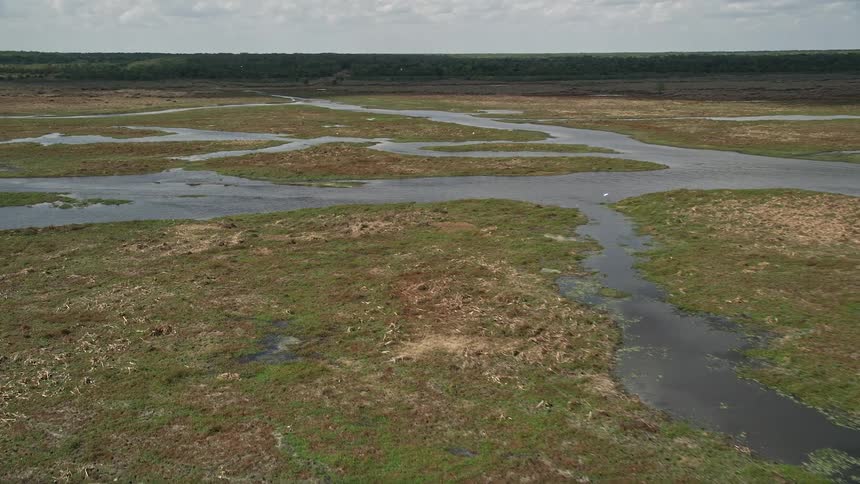Aerial footage pans across rivers and marshland in Cocoa Florida during the summer with partly cloudy skies and wetlands visible