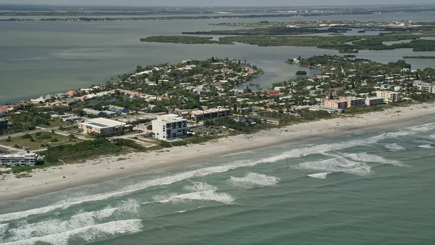 An aerial shot of beaches and coastal communities in Cocoa Beach Florida on a partly cloudy day