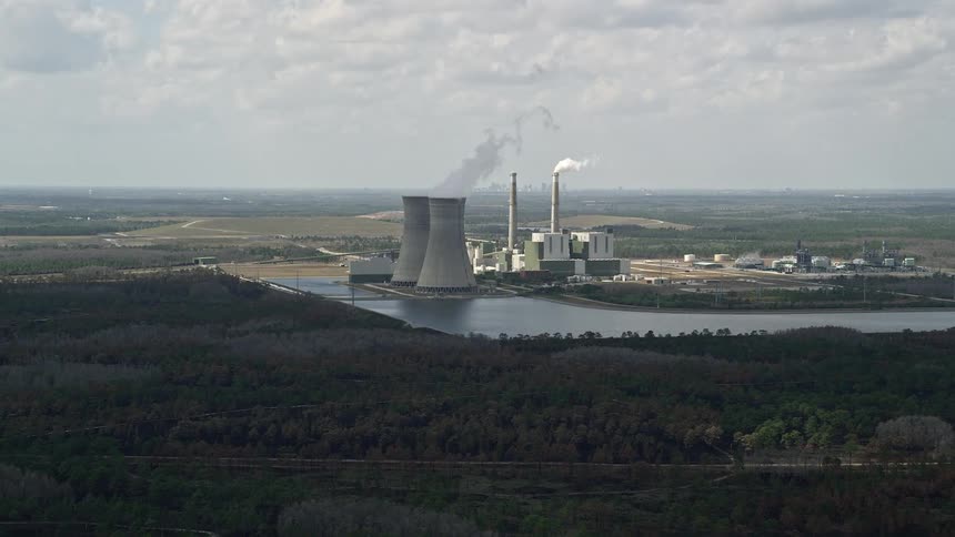 Aerial footage of a coal-fired power plant in Orlando FL during a partly cloudy day showing power generation facilities and energy production