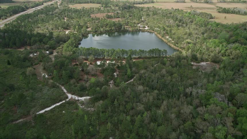 Approaching a small lake and campground surrounded by trees on a sunny day in La Belle Florida during the summer