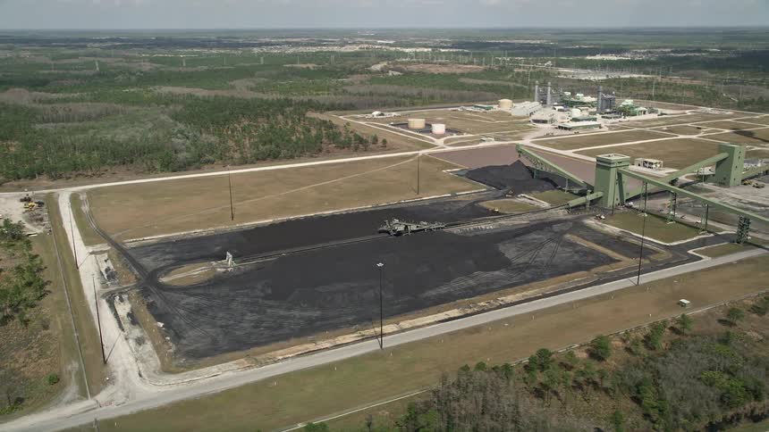 Approaching aerial view of a coal fired power generation facility in Orlando Florida amidst partly cloudy skies during daytime