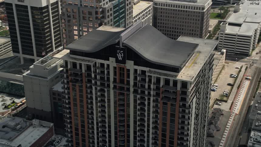 Aerial footage of a high-rise apartment building orbiting in downtown Orlando Florida on a partly cloudy day with a tag of apartment building and downtown areas