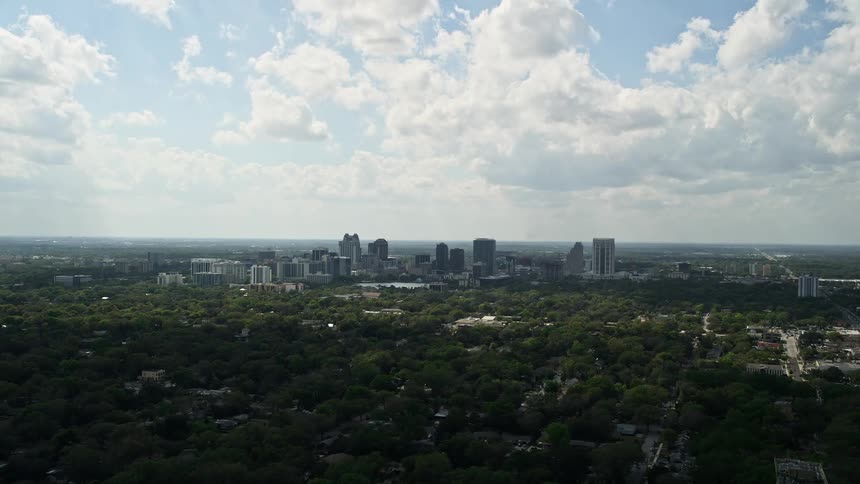 A stunning 5K aerial view of Downtown Orlandos skyline captured from a distance on a partly cloudy day during summer