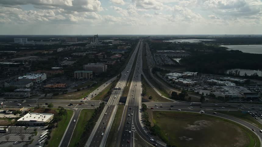 A stunning aerial view of a lightly trafficked interstate in Orlando Florida passing through a quaint suburban neighborhood