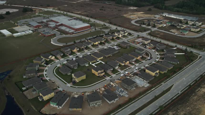 Aerial flyover of suburban homes approaching an elementary school in Clermont Florida on a partly cloudy day