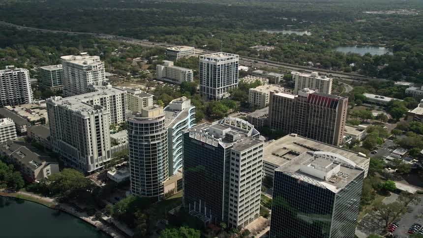 Approaching aerial view of a condo complex and office buildings in Downtown Orlando during a partly cloudy day