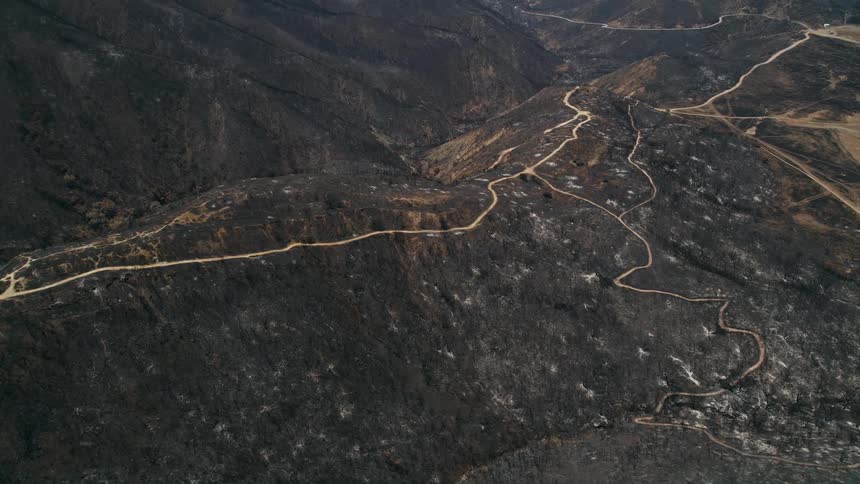 Aerial footage of fire-damaged mountain ridge with dirt roads in the Santa Monica Mountains California