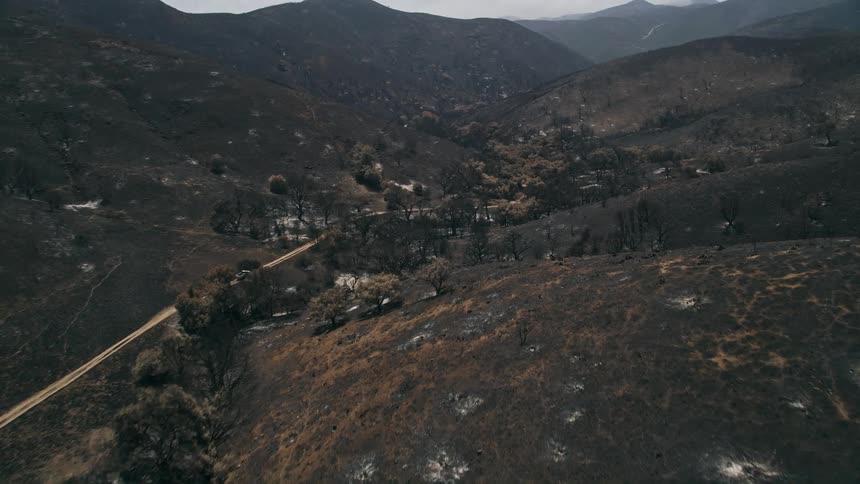 Aerial view of a fire-ravaged mountain road through the Santa Monica Mountains with haze and destruction visible shot in California Outskirts in May 2013