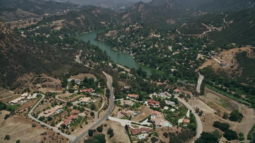 Aerial footage flyover of luxurious homes approaching Malibu Lake in sunny Agoura Hills California