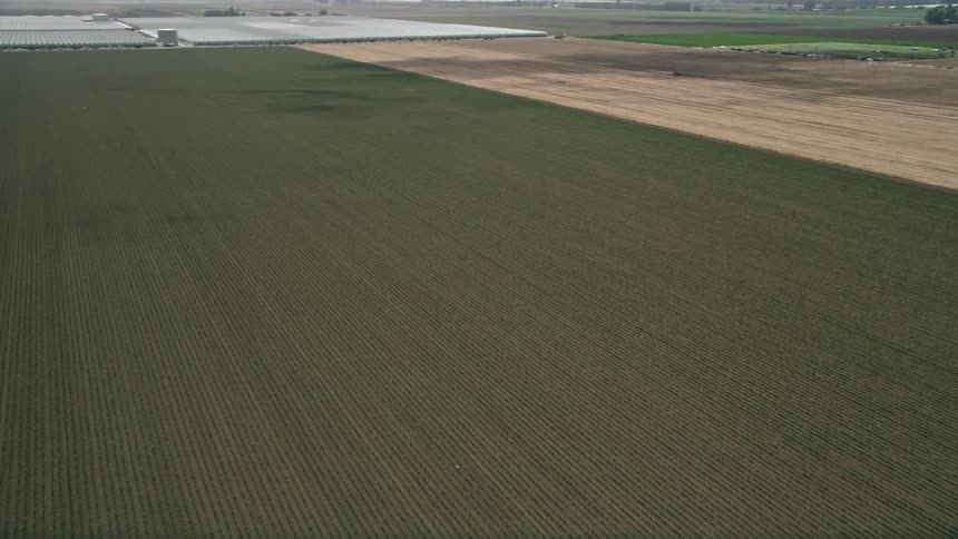 Fly over a freshly plowed field and dirt road in Camarillo California during a sunny day
