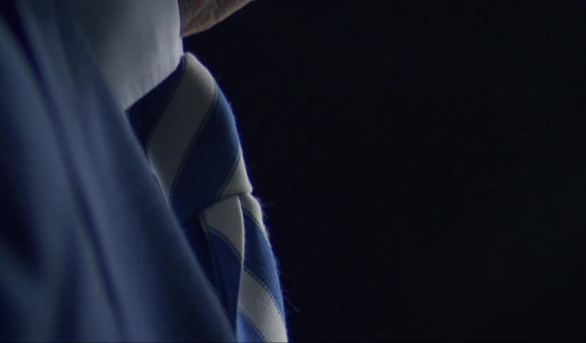 An older man adjusting his tie and coat