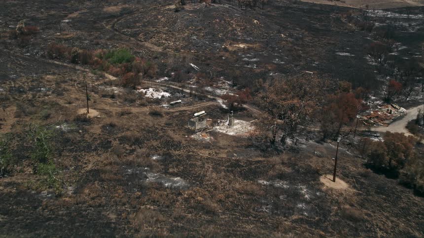 An aerial view shows the aftermath of devastating wildfires revealing charred slopes leading to destroyed rural homes in the Santa Monica Mountains of California