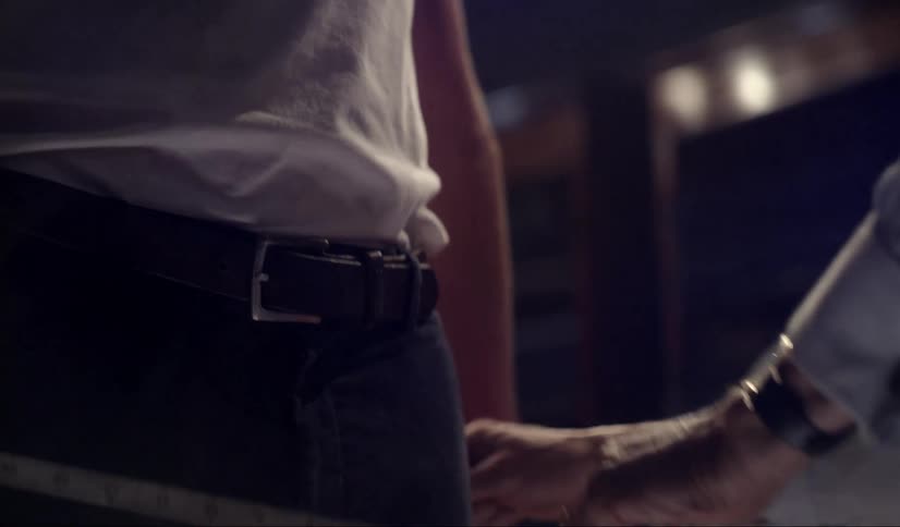 A man holding a tape measure pulls it around the waist of a girl as she stands still