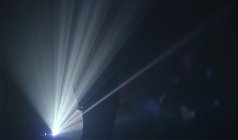 The silhouette of a man standing in front of a light show being displayed behind him