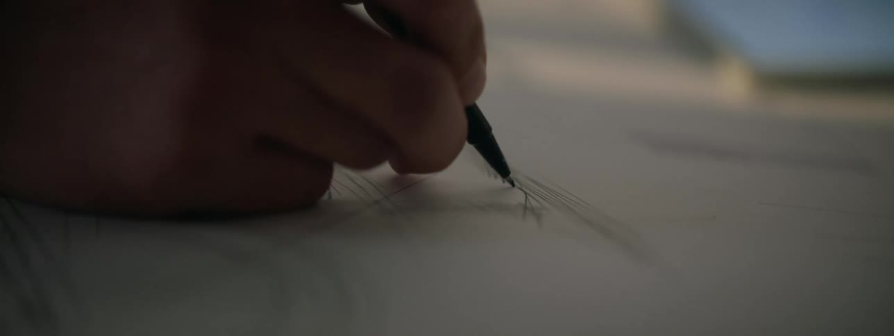 A closeup shot of hands making a pencil sketch on paper