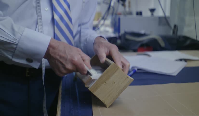 A tailor uses a wooden box to smooth out a ceramic object