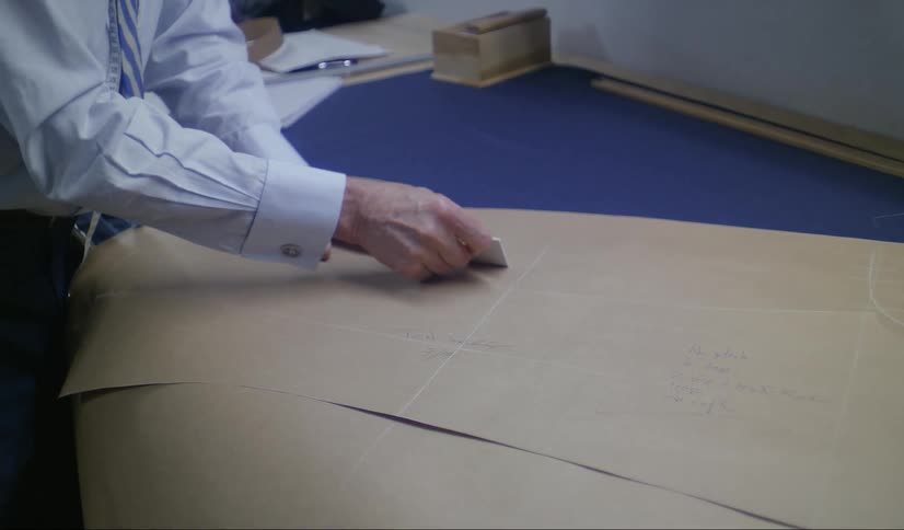 A man using a marking utensil to mark on cardboard that is on a blue table
