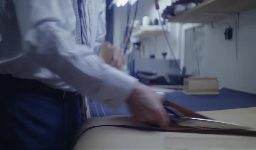 A man trims a large piece of butcher paper with scissors