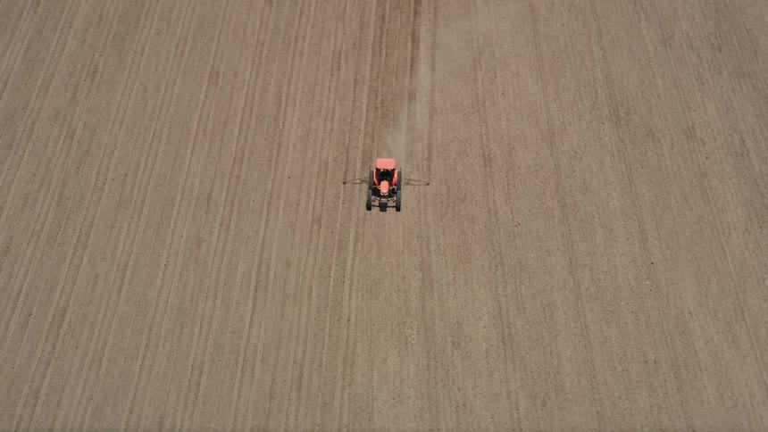 A red tractor tills the soil on a sunny day in Camarillo California