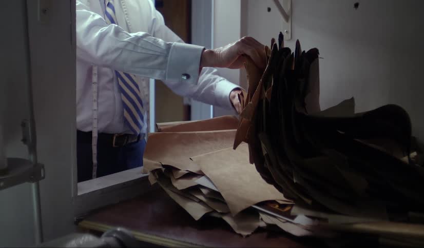 Man standing at a table sorting through a stack of brown paper