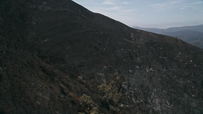 Aerial footage of Santa Monica Mountains shows the devastating aftermath of the wildfires with hazy skies and barren burned foliage covering mountain slopes