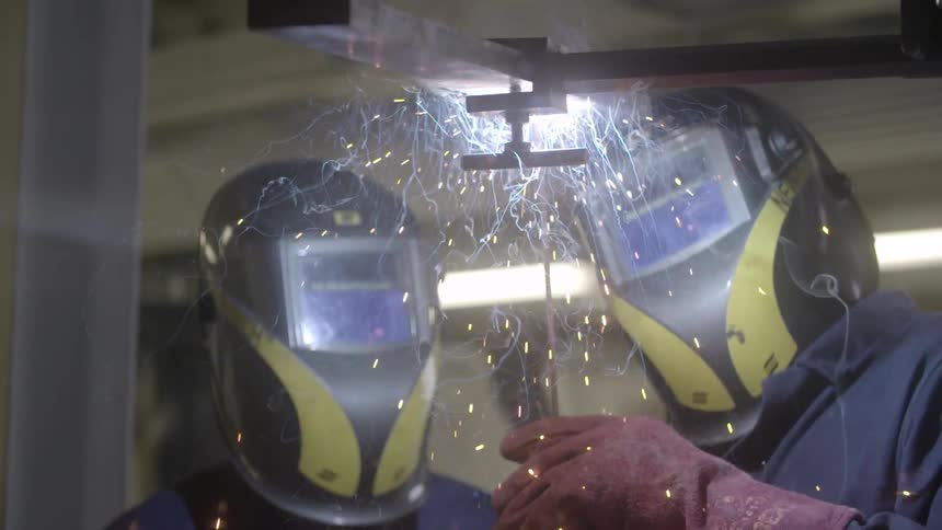 A person is welding as another watches on
