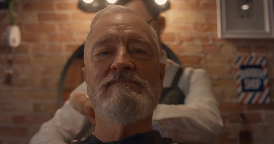 A close up of a man getting a hair cut while the barber massages his neck and rubs in lotion