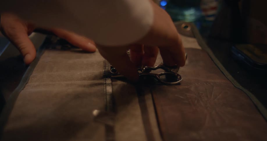 A close up of a person putting scissors into a cloth bag on a counter top