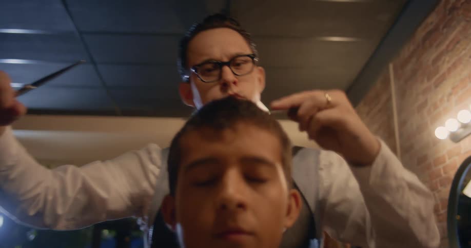 A barber trims the top of a mans hair