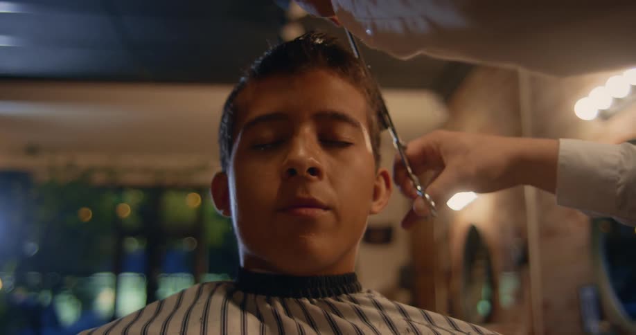 Barber cuts hair of client sitting in barber chair at night