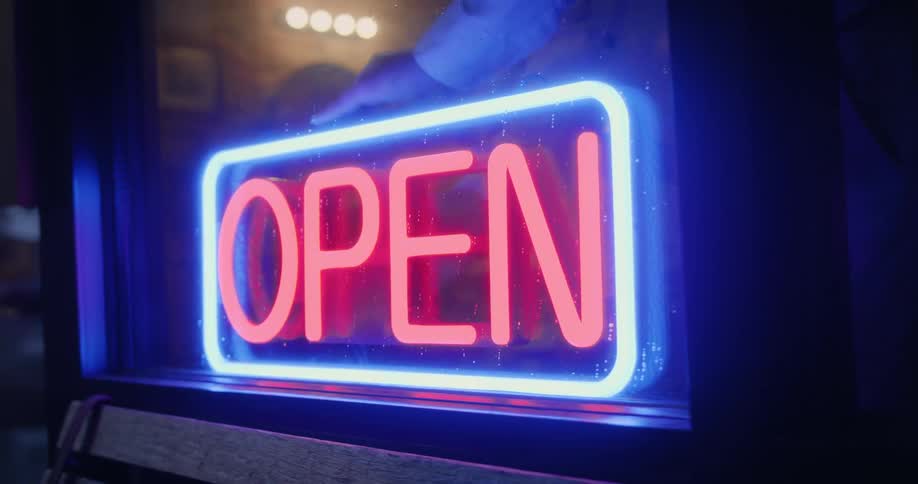 Owner of a barber shop turns off the open neon sign on the front of the store
