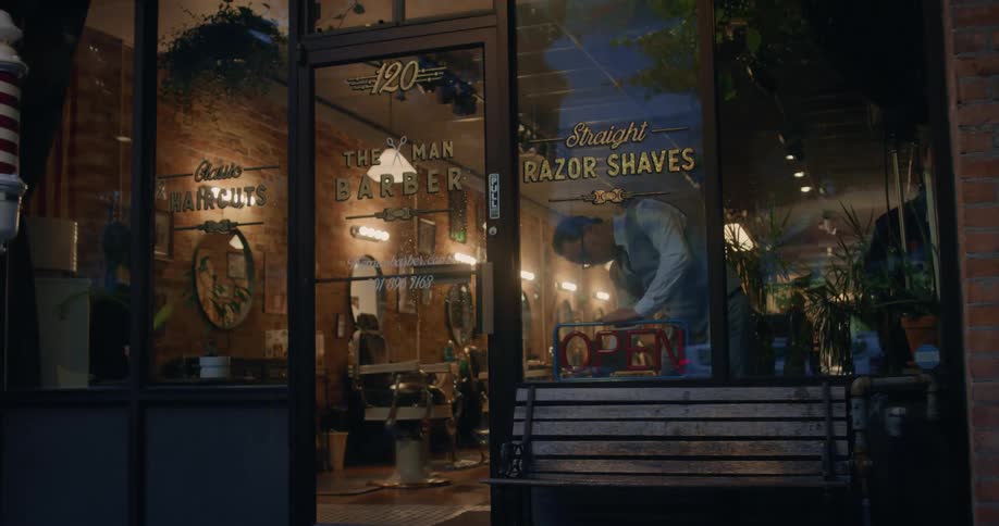 A barber turns off the open sign in the window of a barber shop