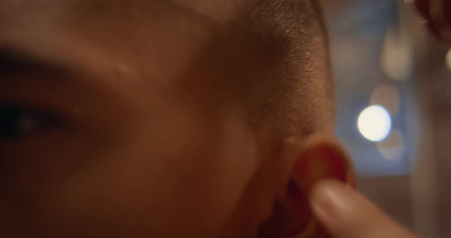Barber uses electric razor cutting boys hair in barbershop