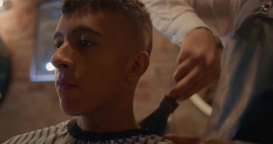 Close up of a hairdresser cleaning the shoulders of a client with a brush