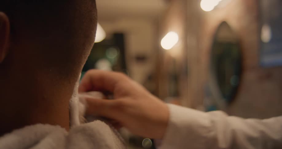 An up close of the back of a customers neck while he gets cream placed on it by the barber
