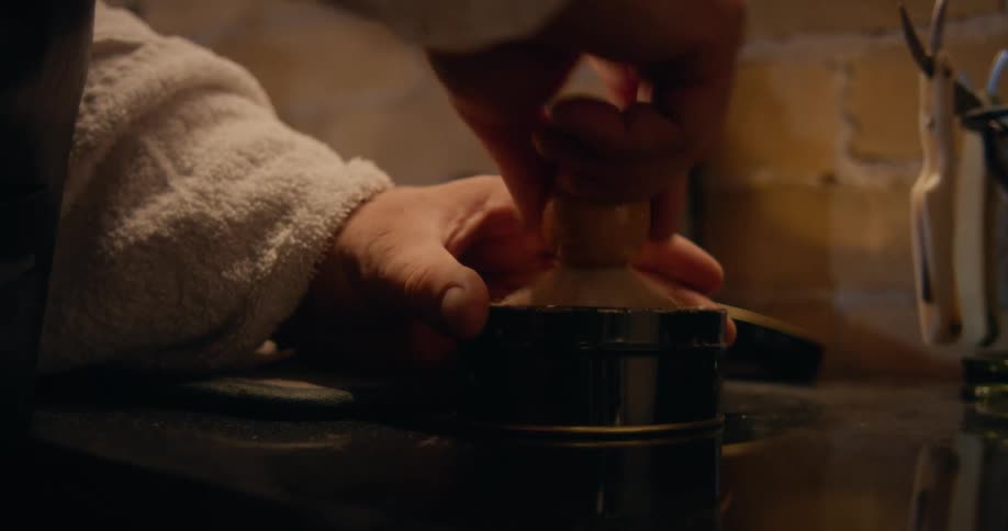 A close up of a person taking a brush and squishing it into a tin canister