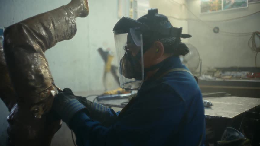 Close up of a sculptor welding a metal statue in his workshop