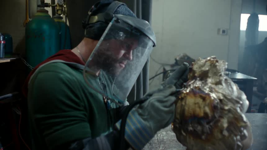 A skilled artist is captured working on a sculpture the man is wearing a protective helmet on his head indicating his focus and commitment to his craft
