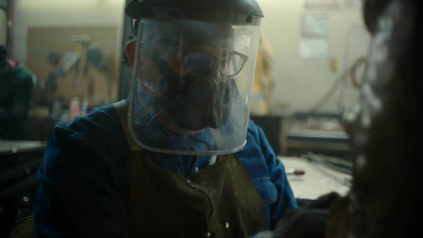 A metal sculptor wearing a protection mask to work on a sculpture