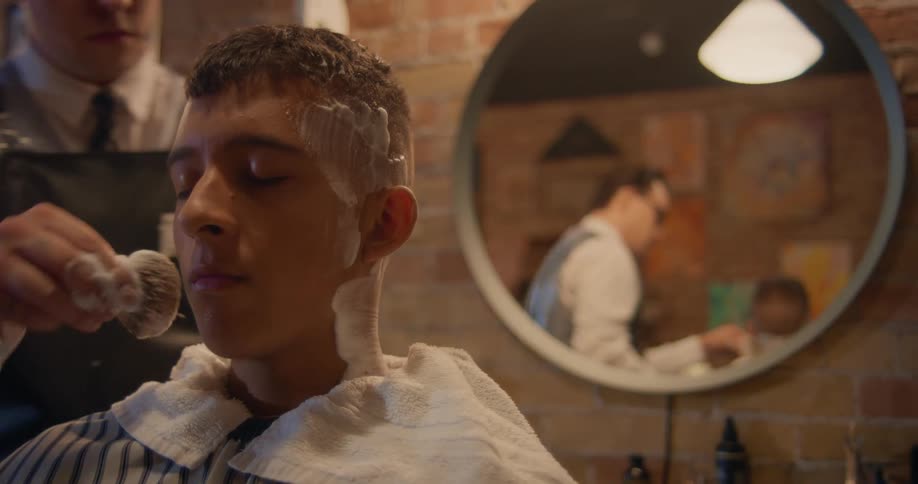 Close up of a barber applying foam on the head of a customer