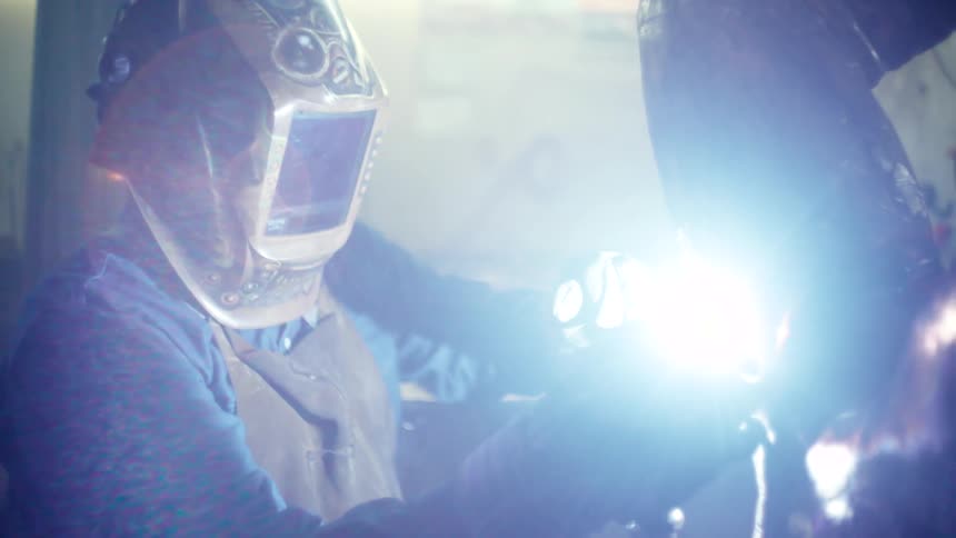 Man working on a metal sculpture soldering and welding human figure