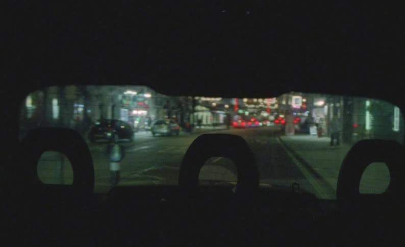 Bright electric light shines onto city street at night outside vehicle